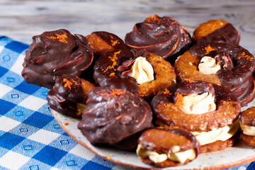 Marshmallows in chocolate on plate on a blue napkin in a white square background, closeup, horizontal