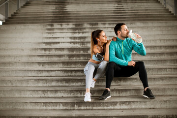 Young couple resting during training with bottle of water