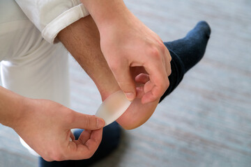 Painful Heel wound on mans feet caused by new shoes. mans hands