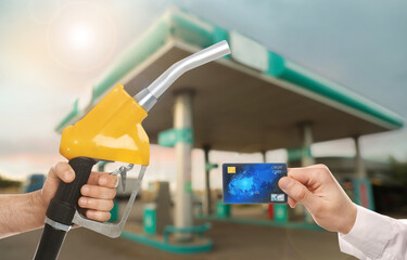 Man holding credit card and worker with fuel nozzle at gas station, closeup. Cashless payment