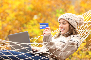 Happy woman buying online on hammock in autumn holiday