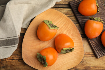 Tasty ripe persimmons on wooden table, flat lay
