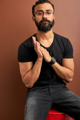 handsome arabic male posing at camera while sitting on barrel in studio. mixed race cool male...