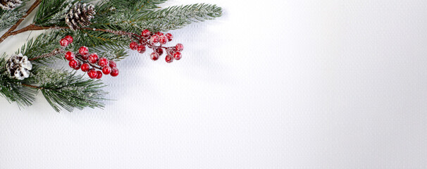 Obraz na płótnie Canvas Christmas fir branch with berries and cones, sprinkled with snow on a light textured background close-up with copy space