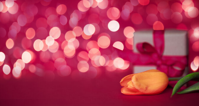 Valentine's day concept. Yellow tulipan and gift box on a red bokeh background. Greeting card, banner, copy space