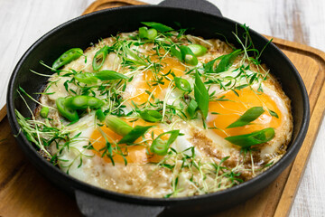 scrambled eggs with greens sprouts and green onions in a pan