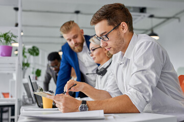 Obraz premium business team coworking brainstorming in the office, focus on concentrated male in eyeglasses with document