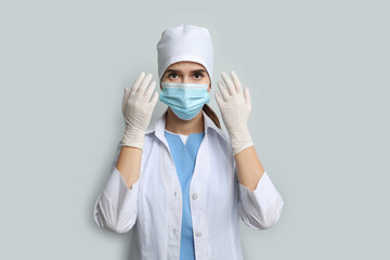 Fototapeta na wymiar Doctor in protective mask and medical gloves against light grey background