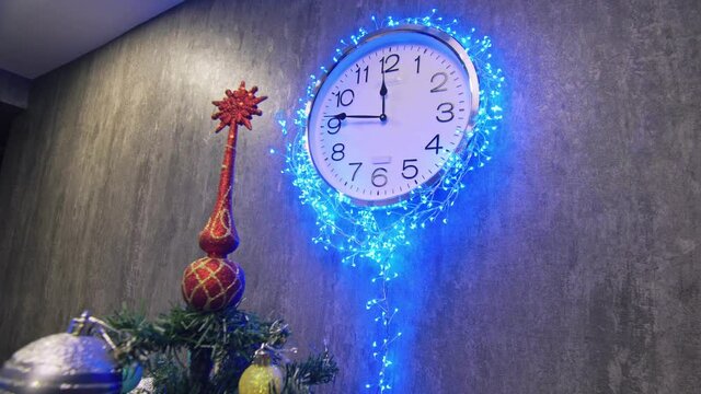 Clock and christmas tree, balls, toys. Timelapse New Year. The clock is hanging on the wall. Time on the clock is 23.45 to 00.00. Last 15 minutes of this year.