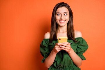 Photo of positive woman hold telephone look empty space wear dark shirt isolated on orange color...