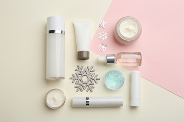 Flat lay composition with cosmetic products on pink and beige background. Winter care