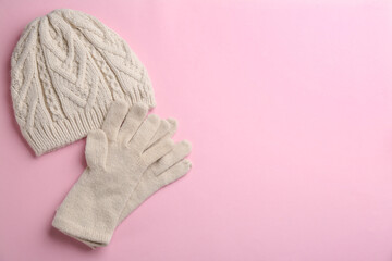 Woolen gloves and hat on pink background, flat lay. Space for text