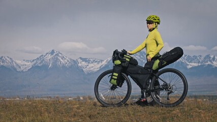 The woman travel on mixed terrain cycle touring with bikepacking. The traveler journey with bicycle...