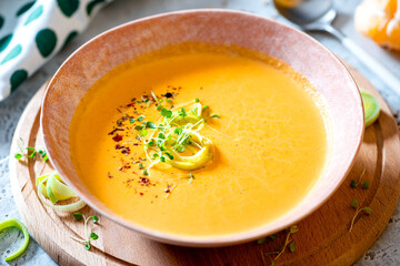 Tasty carrot creamy soup with herbs and spices in a bowl close-up. Soft focus. Autumn or winter food. Pureed vegetable soup.