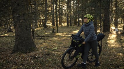 The woman travel on mixed terrain cycle touring with bike bikepacking. The traveler journey with bicycle bags. Magic forest park.