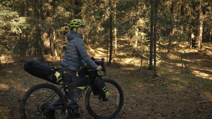 The woman travel on mixed terrain cycle touring with bike bikepacking. The traveler journey with bicycle bags. Magic forest park.