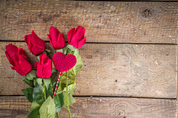 Naklejka na ściany i meble Red rose flowers bouquet with red heart on wooden background. Valentine's day greeting card background. Copy space Top view