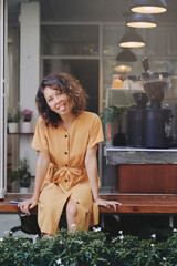 young woman wearing yellow dress shows tongue while sitting at coffee shop
