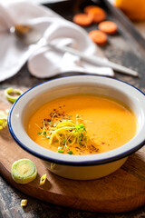 Tasty carrot creamy soup with herbs and spices in a bowl close-up. Soft focus. Autumn or winter food. Pureed vegetable soup.