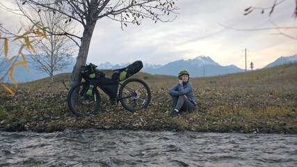 Obraz premium The woman travel on mixed terrain cycle touring with bikepacking. The traveler journey with bicycle bags. Sport tourism bikepacking.