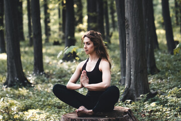 Young girl practices yoga in the forest, the concept of enjoying privacy and concentration - 396376852