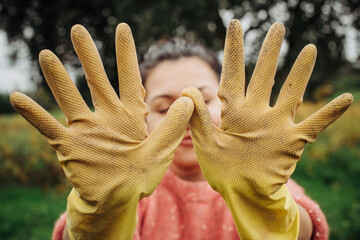 Close up of open hands with yellow rubber gloves dirty after work on the field.