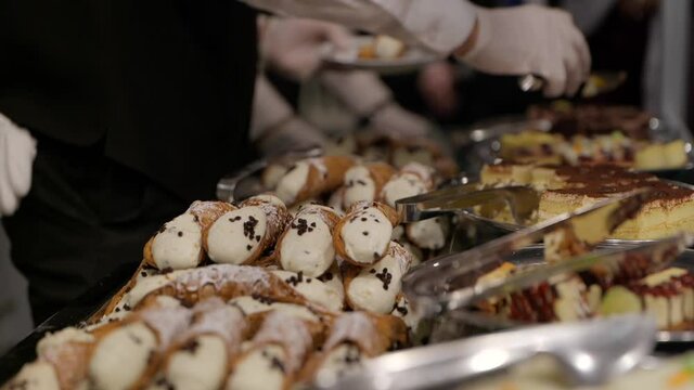 Close up of waiter&rsquo;s hand serving Italian cannolis 