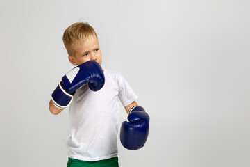 little boxing fighter boy in blue boxer gloves child dreams of becoming a boxing champion. copy space