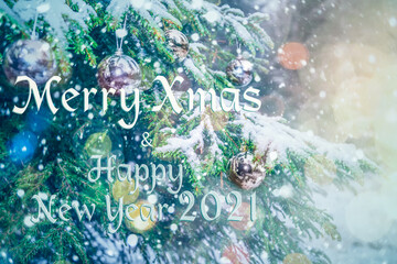 Obraz na płótnie Canvas Merry Christmas and Happy New Year 2021! Blurred background of Christmas tree in snowfall decorated with silver balls, lights. Forest in snowflakes. Bokeh. Gift Greeting postcard. Wallpaper. Banner.