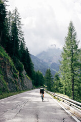 Professional road cyclist on fast and light carbon bicycle descends mountain road in Alps Dolomites. Fit and athletic man on recreational ride trip or training camp, enjoy time outdoors on bike