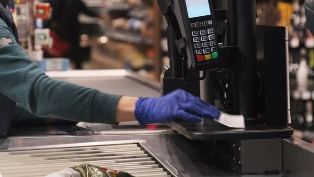 Payment through the Terminal in the Store. Cashier in Gloves with the Terminal