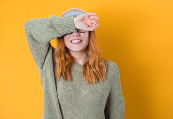 Shame. Close up young woman covering face with hands, isolated on yellow background. Ashamed girl.
