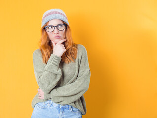 Skeptical young woman thinks while looks to side. Closeup portrait of doubtful girl with confused expression, isolated on yellow background. Studio shot