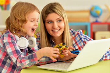 Mother and daughter using laptop together playing game