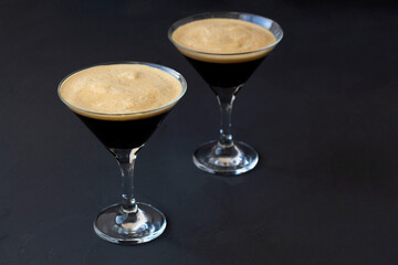 Espresso Martini cocktail garnished with coffee beans on dark table. Two martini glasses on a black background. alcohol drinks. copy space. top view