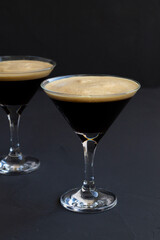Espresso Martini cocktail garnished with coffee beans on dark table. Two martini glasses on a black background. alcohol drinks. copy space. vertical