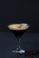 Espresso Martini cocktail garnished with coffee beans on dark table. Martini glass on a black background. alcohol drinks. copy space. vertical