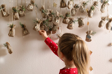 Little girl taking gift from New Year advent calendar indoors