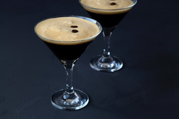 Espresso Martini cocktails garnished with coffee beans on table. Two martini glasses on a black background. alcohol drinks