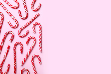 Sweet Christmas candy canes on pink background, flat lay. Space for text