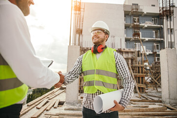 Male engineer shaking hands with colleague on construction site