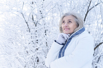 Beautiful senior woman posing in snowy winter park