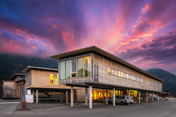 Fototapeta na wymiar Sustainable wood office building on pillars with parking spaces underneath at sunset