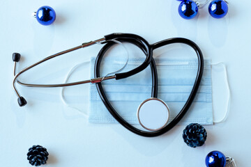 phonendoscope in the shape of a heart and a medical mask on a light background, New Year's toys....