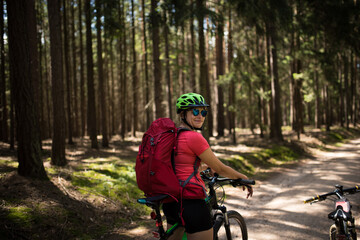 Young woman with helmet riding mountain bicycle in the forest.