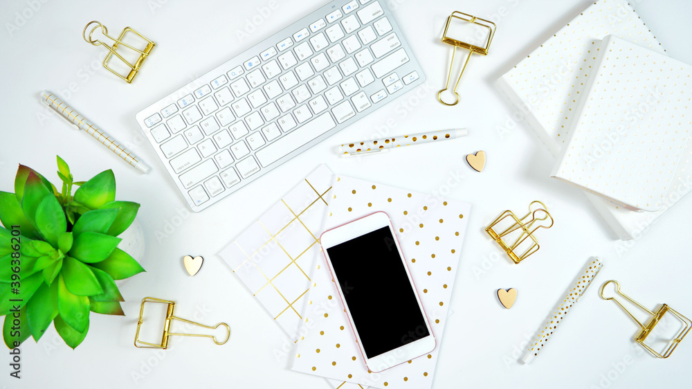 Wall mural stylish white and gold theme desktop workspace with keyboard, notebooks and smart phone. top view bl