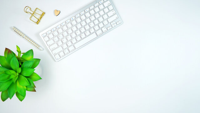 Stylish white and gold theme desktop workspace with keyboard, notebooks and smart phone. Top view blog hero header creative composition flat lay.
