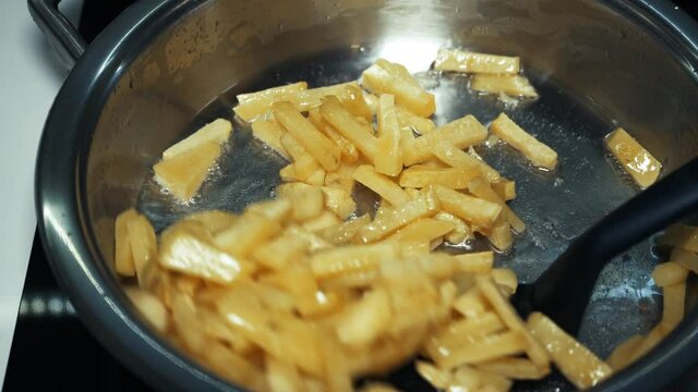 Flips fried potatoes in a pan