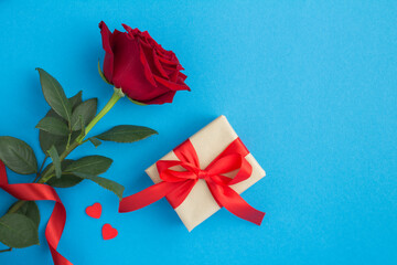 Top view of gift box and red rose on the blue background with copy space