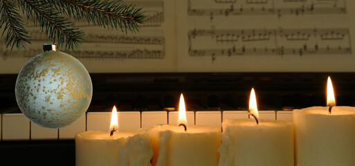 christmas decoration with four burning candles, spruce branch, piano and music paper